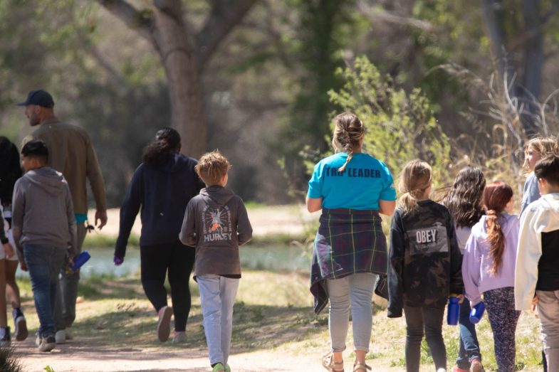 BioBlitz trip leader walking around with a group of kids, back facing the camera